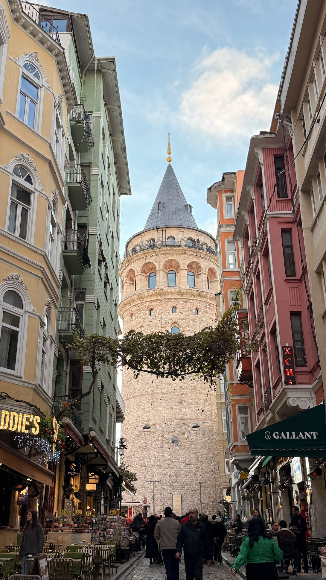 Galata Tower framed by colourful buildings on a busy Istanbul street.
